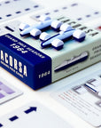 Split-color playing pieces for a board game, with the top half predominantly white and the other blue, arranged on a game box with cards.