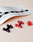 open Lacorsa rulebook with diagram, a red and black racecar and die