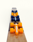 Wooden game board with orange and blue plastic race car pieces on a white background