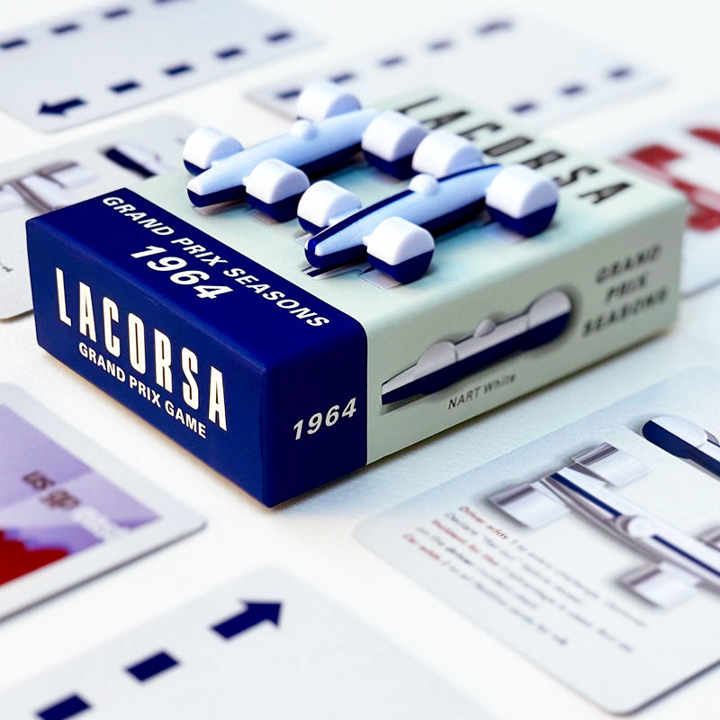 Split-color playing pieces for a board game, with the top half predominantly white and the other blue, arranged on a game box with cards.