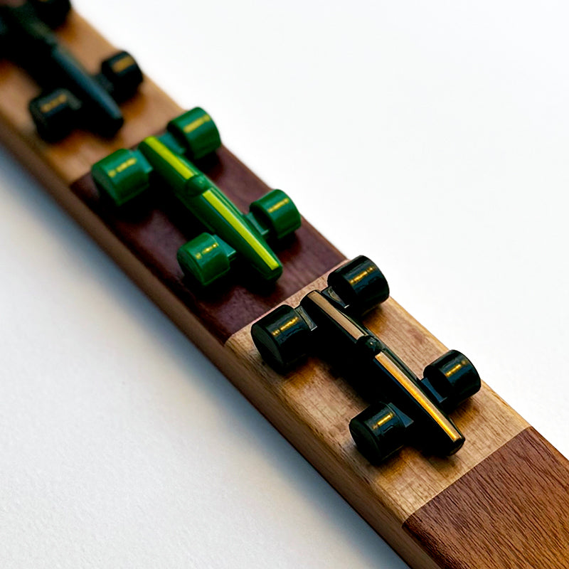 A close-up of the Lacorsa Grand Prix Board Game set, showing shiny green game pieces representing racecars on a wooden board.