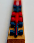 Shot of Blue race car on wooden checkerboard head on with red and blue cars behind