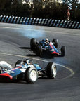Two vintage Formula 1 cars racing on a track with a blurred background